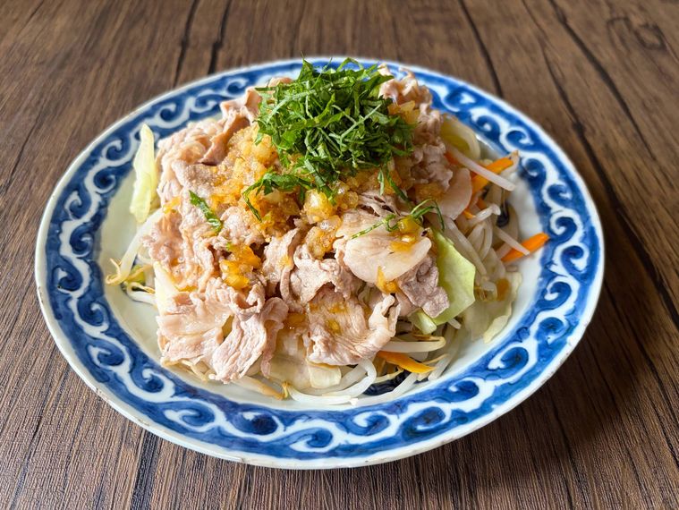 和皿に盛られた冷しゃぶにごまポン酢玉ねぎドレッシングをかけたもの