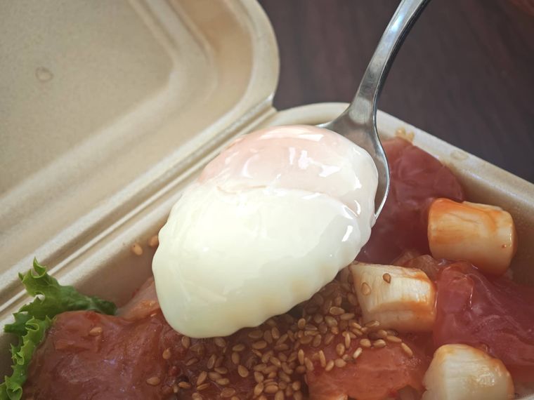 ヤオコーやみつきポキ丼の温泉卵をすくっている様子