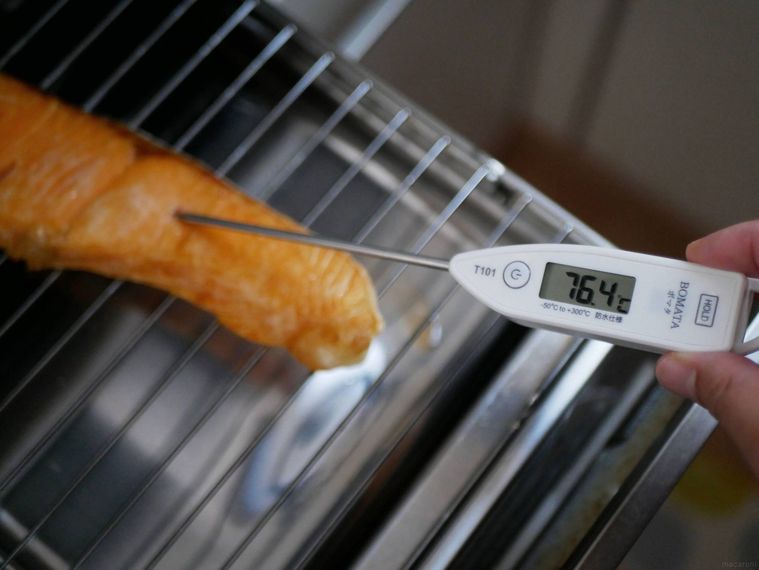 鮭の切り身をグリルで焼きながら、中心温度計を刺す様子