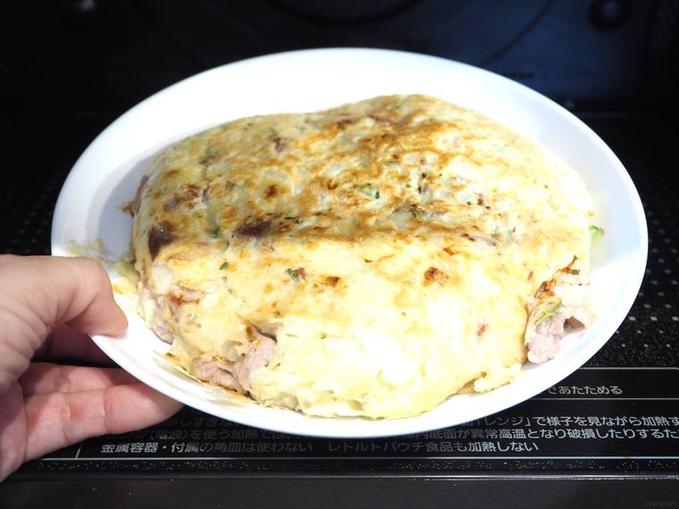 白い皿に盛り付けたお好み焼きを電子レンジに入れている様子