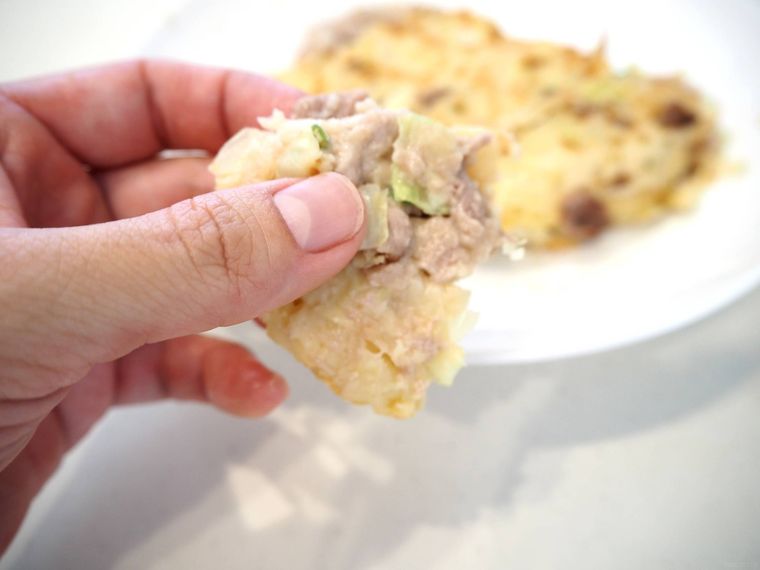 生焼けのお好み焼きを手で持っている