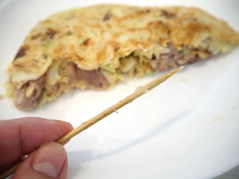 生焼けのお好み焼きに竹串を刺した様子