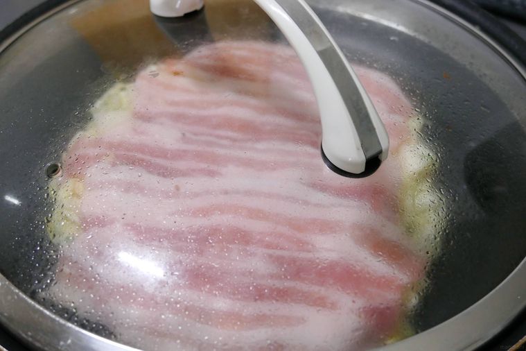 お好み焼きをフライパンでふたをして焼いている様子