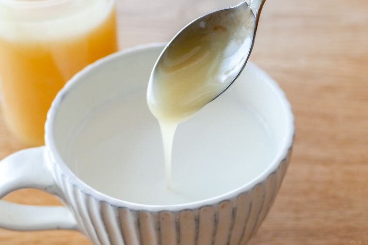 ホットミルクにはちみつをスプーンで垂らし入れる様子