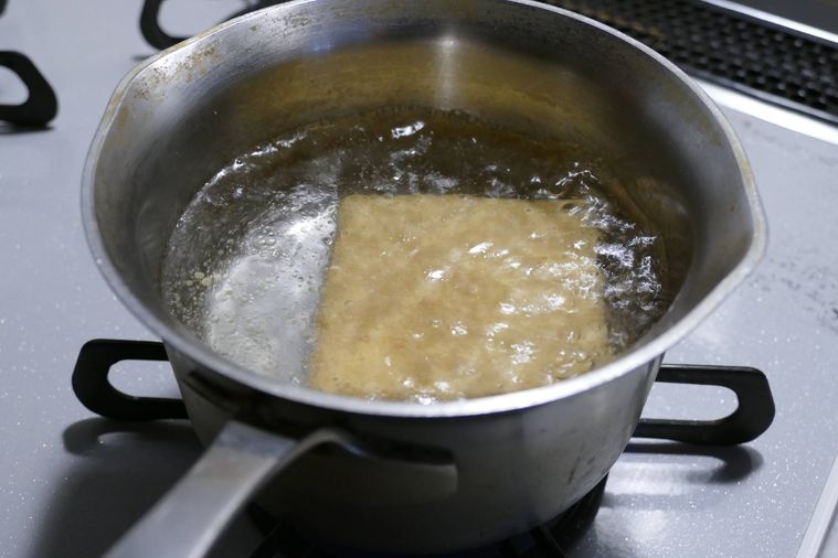 鍋で沸かした湯に厚揚げを入れてゆでる様子