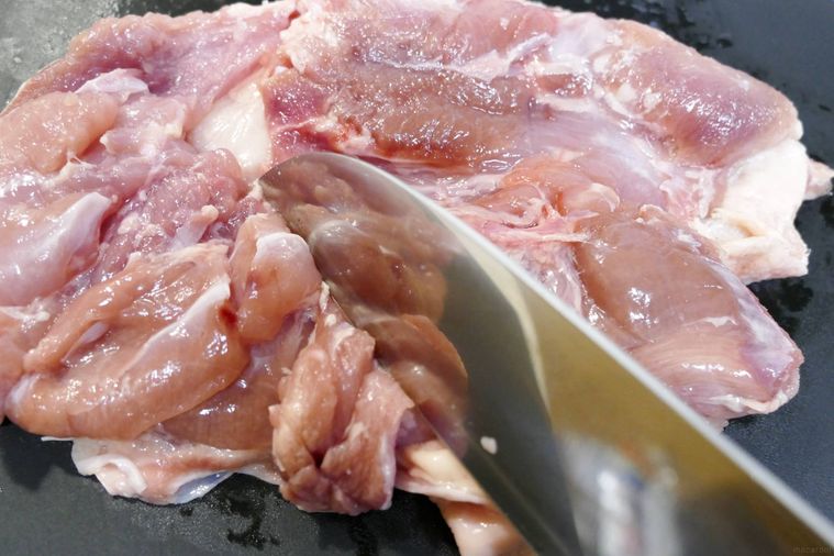 鶏もも肉の細い筋に包丁を入れる様子