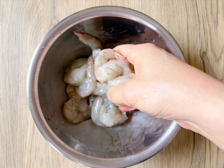ボウルに入れたむきえびに塩と片栗粉をもみ込む様子