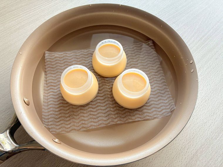 フライパンに並んでいる耐熱プラスチック容器に入ったプリン