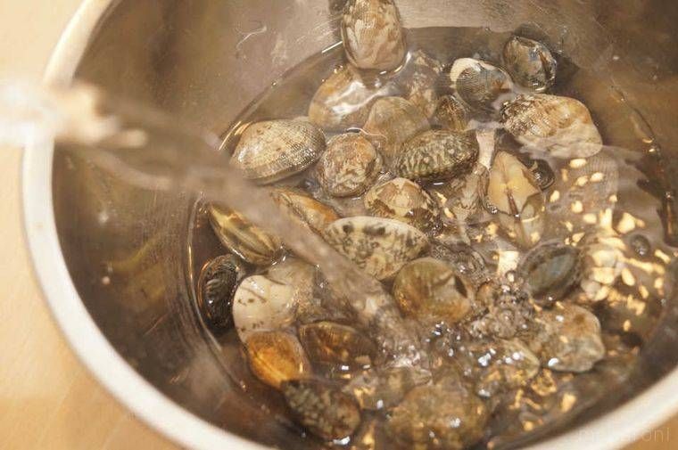 ボウルにあさりと水、熱湯を入れる様子