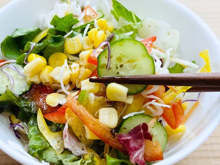 Calbee ポテトチップス のりしお味ドレッシングがかかったサラダを箸でつまんでいる様子