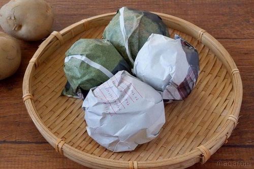 ザルにおかれた新聞紙で包んだじゃがいも