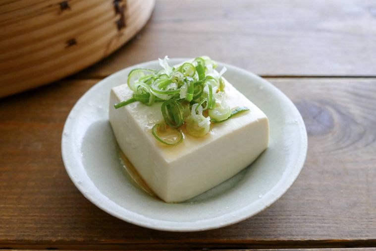 せいろ蒸し豆腐に小口ねぎとごま油、塩をかけた様子