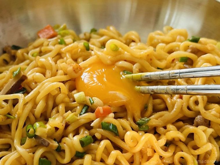 まぜそばにトッピングした卵黄をつぶしている様子