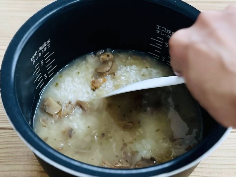 炊飯釜に米、ママー 香味野菜たっぷりのあさりコンソメ、水を入れ、かき混ぜている様子