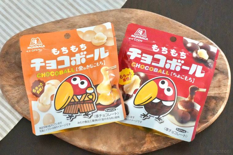 木のカッティングボードにのったもちもちチョコボールのオレンジ色と赤色のパッケージとストライプの布