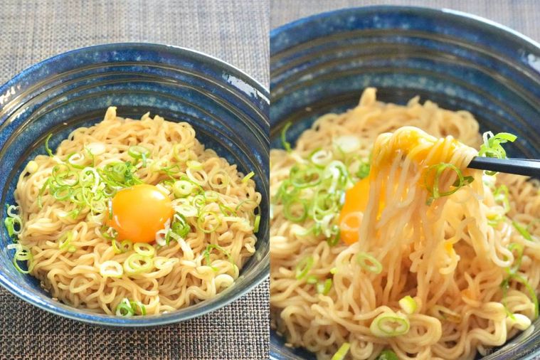 青いラーメン丼に盛られた卵黄とねぎのせ油そばを黒い箸で食べる様子