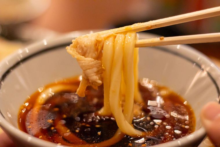 丸亀製麺旨辛豚つけ汁うどんを箸上げしている