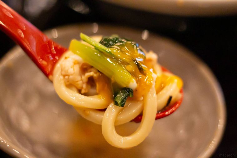 温泉玉子を絡めた丸亀製麺旨辛豚つけ汁うどんを箸上げしている