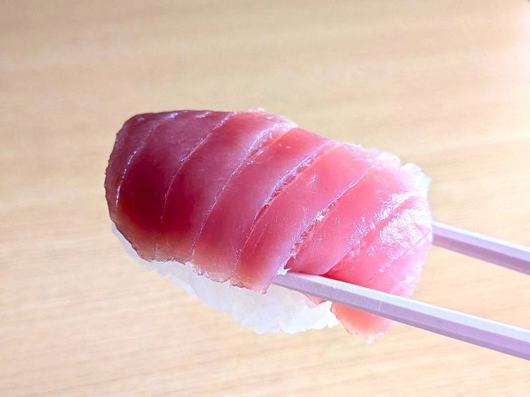 箸で持った上にぎりのマグロ