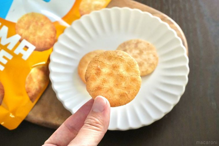 オレンジ色のパッケージ袋とファミマ味のソフトせんべいを指先で持つ様子