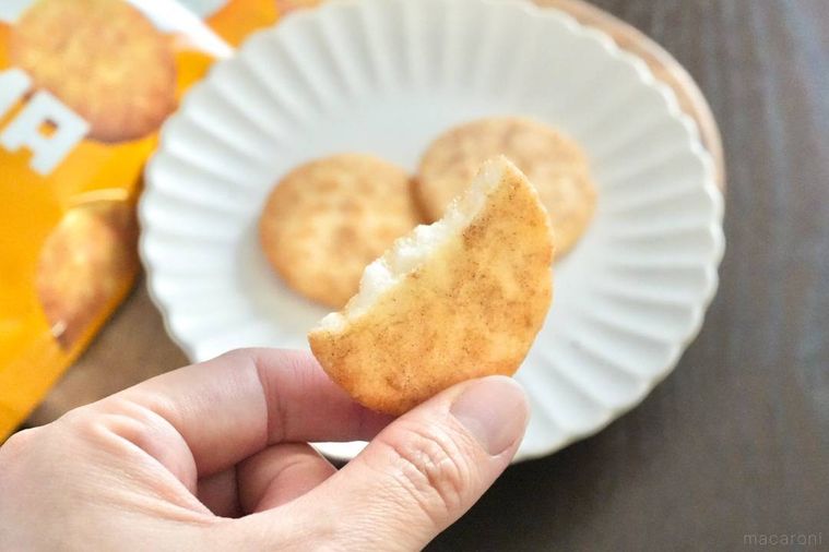 木のカッティングボードにのったファミマ味のソフトせんべいを手で持つ様子