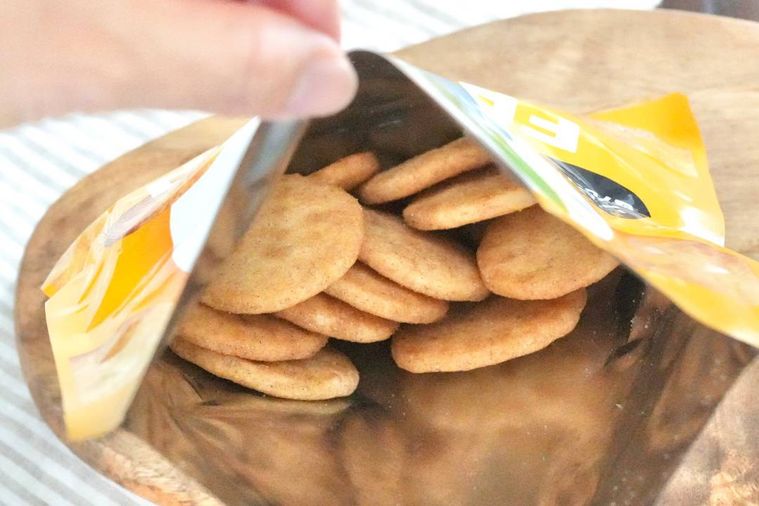 ソフトせんべいのオレンジ色のパッケージの袋をゆびでつまんで開ける様子