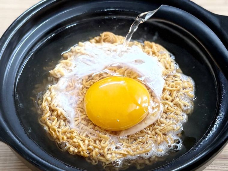 チキンラーメンの卵に熱湯をかけている様子