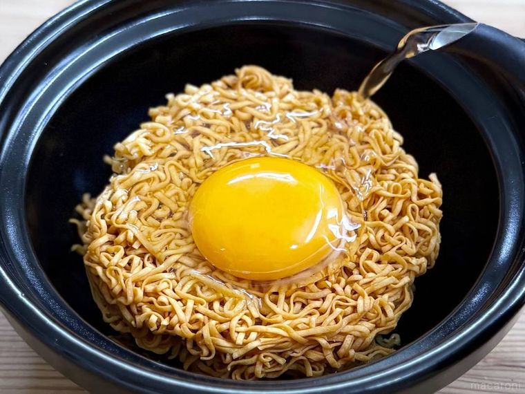 卵を割り入れたチキンラーメンにお湯を注いでいる様子