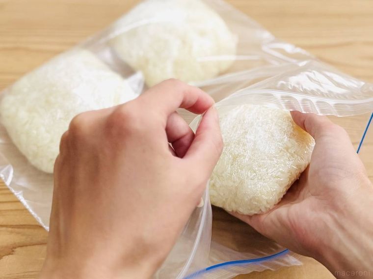 バターライスをラップで包み、冷凍用保存袋に入れようとしている様子