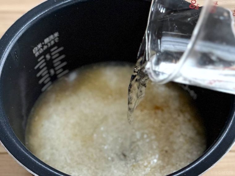 米が入った炊飯釜に水を注いでいる様子
