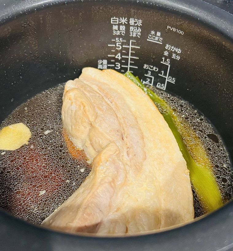 炊飯器に豚バラブロック肉と長ねぎ、しょうが、調味料を入れた様子