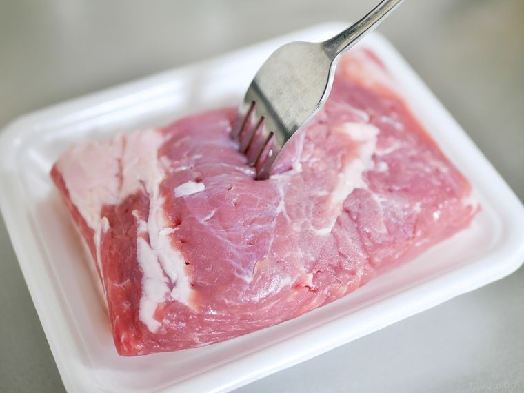 豚肉のブロックにフォークで穴をあけている様子
