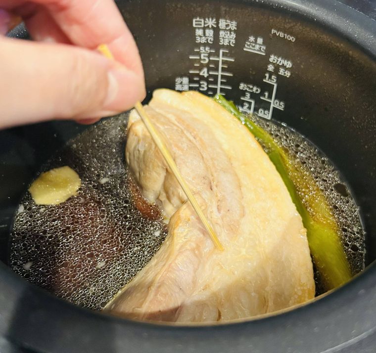 豚バラブロック肉に竹串を刺して火の通りを確認している様子