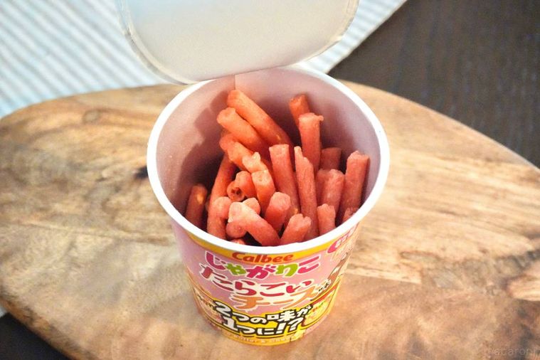 木のカッティングボードにのった黄色とピンク色のじゃがりこのパッケージと中身