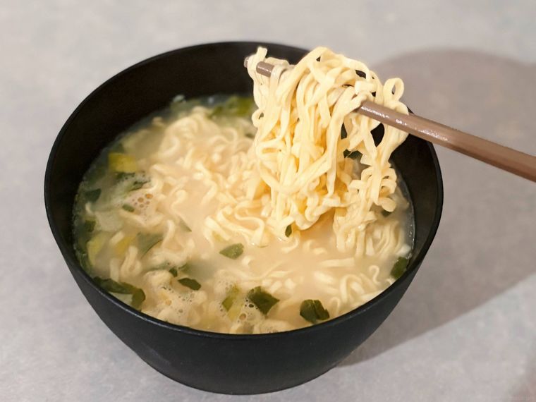 お椀に入った麺を箸で上げる様子