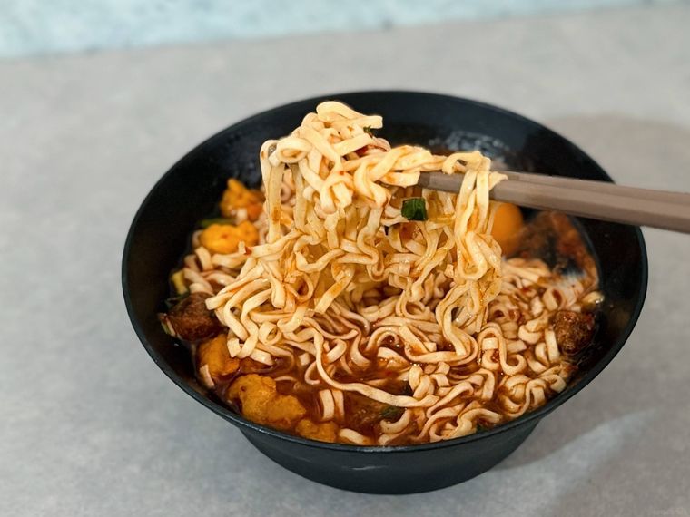 お椀に入った麺を箸で上げる様子