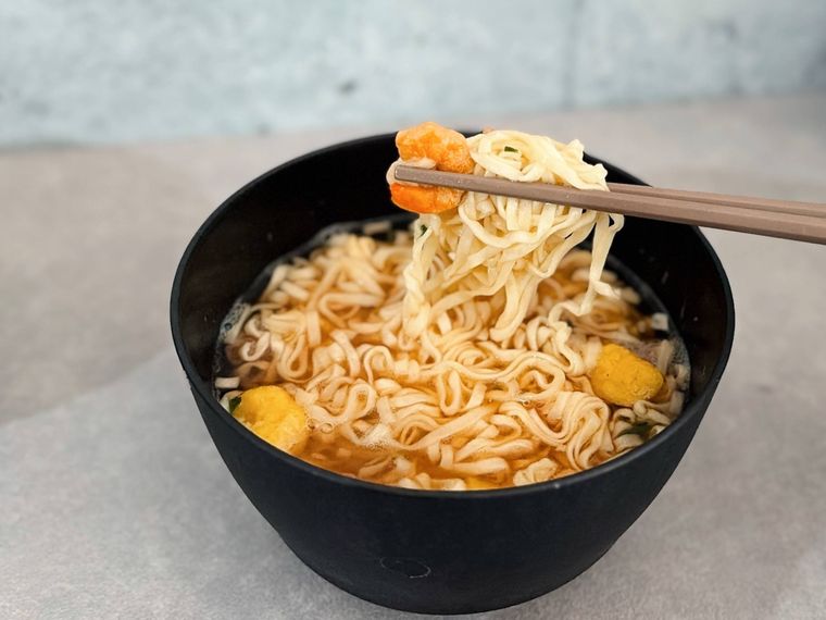 お椀に入った麺を箸で上げる様子