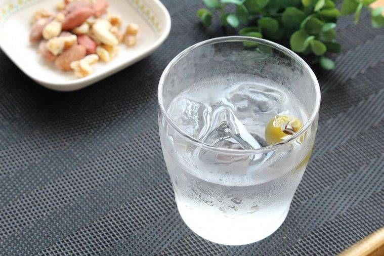 グラスに入ったジンと皿に盛られたナッツ