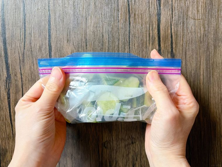 きゅうりのビール漬けが入ったジッパー付き保存袋の空気を抜く様子