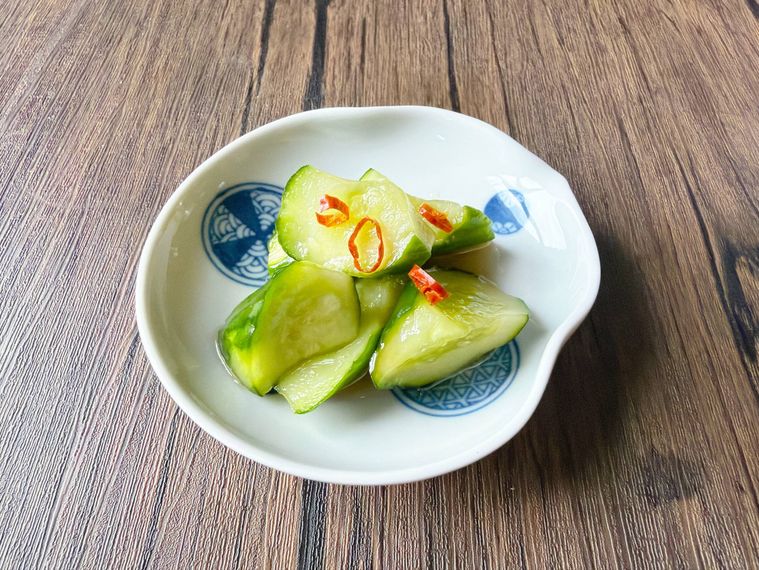 小皿に盛られたきゅうりのビール漬けにごま油、ラー油、鷹の爪を加えたもの