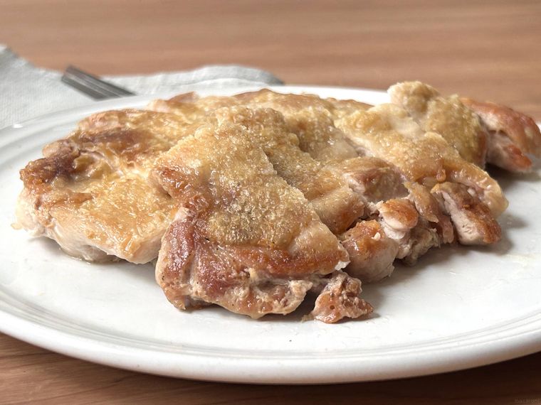 チキンステーキが白い皿に盛り付けられているところ