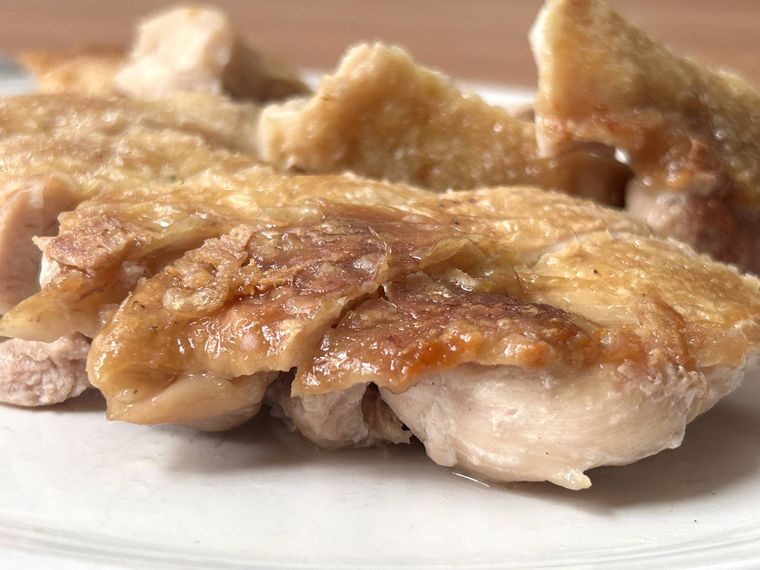 チキンステーキが白い皿に盛り付けられているところ
