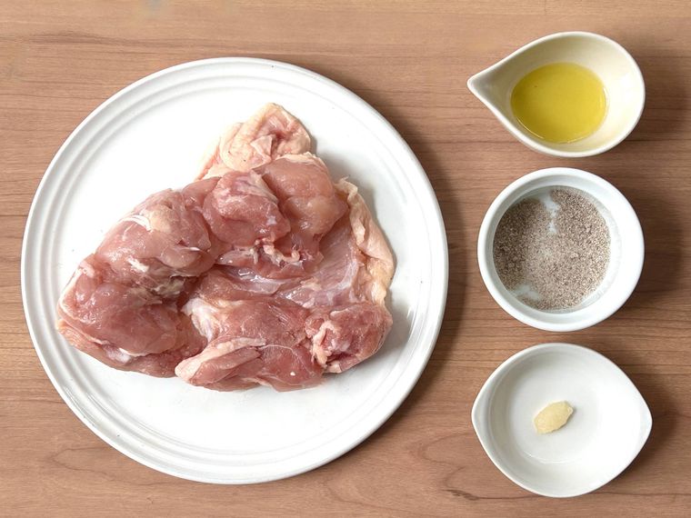 鶏もも肉とにんにくすりおろし、味付け塩こしょう、オリーブオイルが並んでいるところ