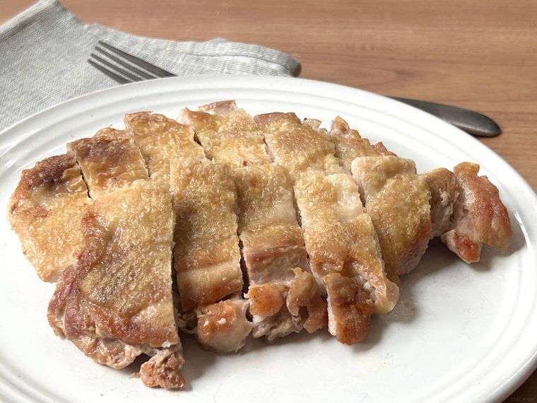 チキンステーキが白い皿に盛り付けられているところ