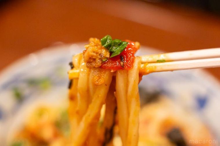丸亀製麺ガツンとニンニク肉辛まぜうどんひと口ごはん、トマト酢つきを箸上げしている