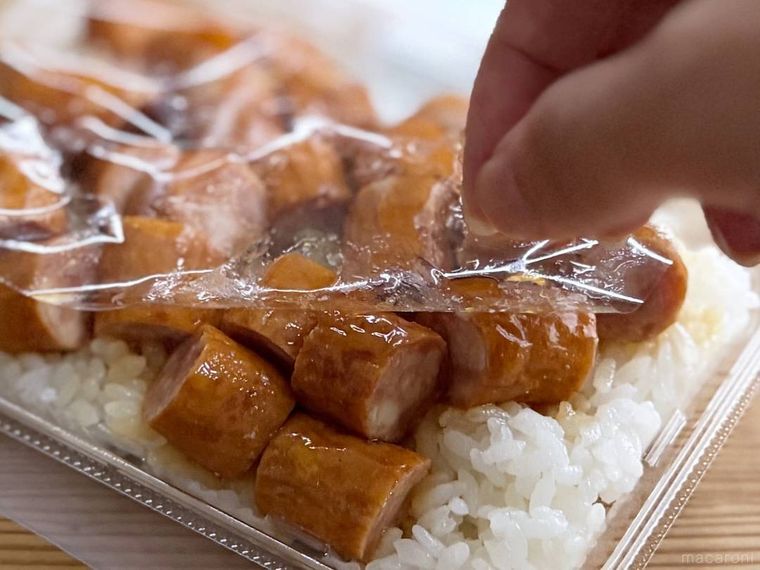 一点突破すぎ敷き詰めごはん てりやきソーセージのフィルムを剥がしている様子