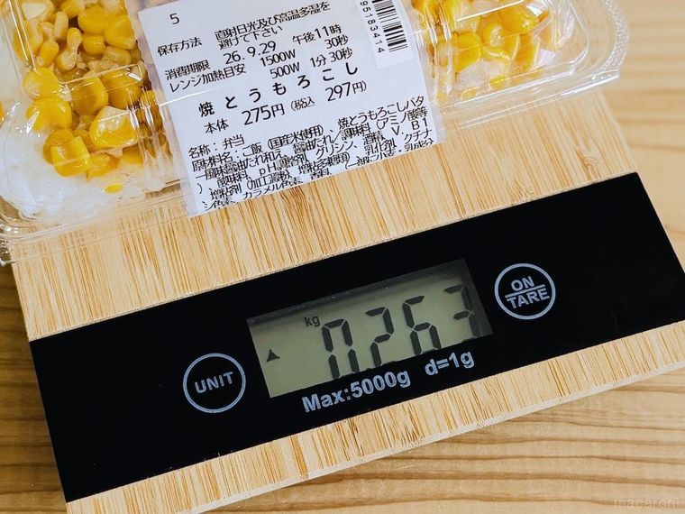 ローソンの一点突破過ぎ敷き詰めごはん 焼とうもろこしをスケールにのせた様子