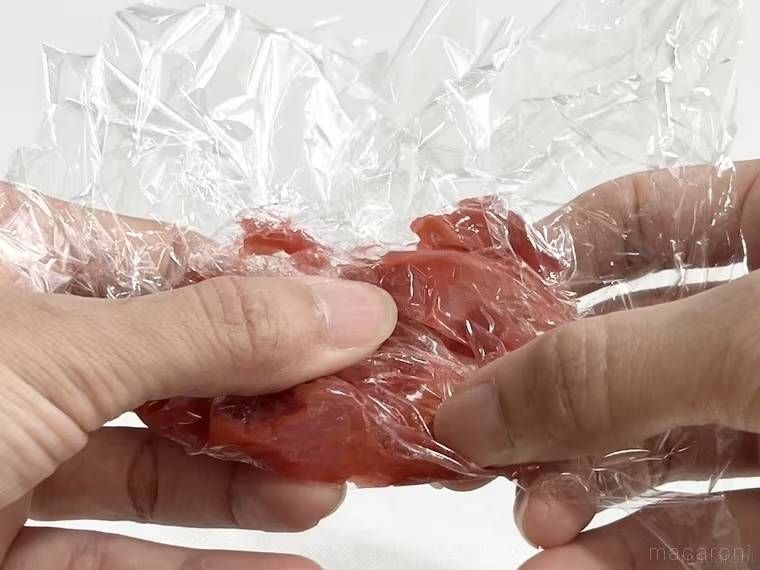 梅干しをラップで包み、手でもんでいる様子