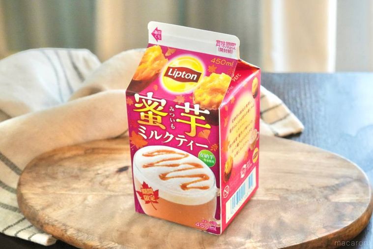 木のカッティングボードにのった蜜芋ミルクティーのパック飲料のさつまいも色のパッケージ