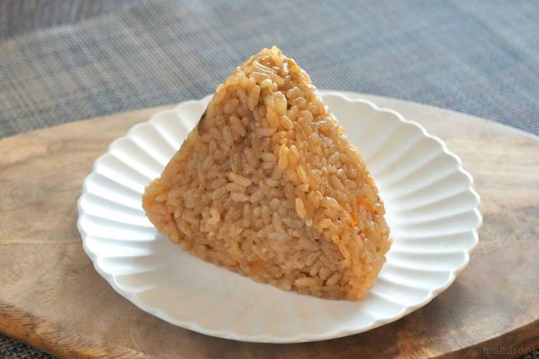 木のカッティングボードと白い皿にのった冷凍の鶏めしおにぎり